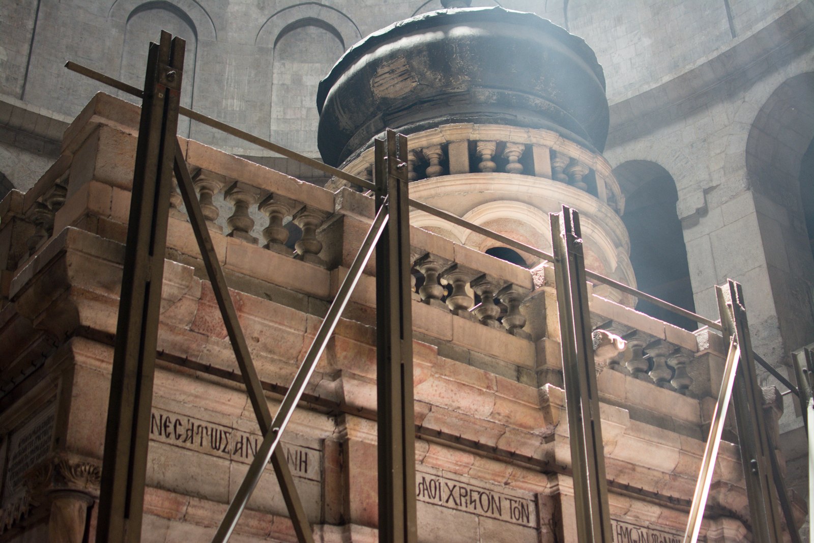 The stone shrine built over the tomb, lit by shafts of light from the dome above, with pilgrims waiting at its door